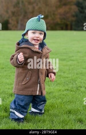 Adorabile ragazzo di un anno che grinning in modo allegro ed eccitato per essere corsa circa all'aria aperta: Sheffield Park, East Sussex, Inghilterra, Regno Unito. MODELLO RILASCIATO Foto Stock