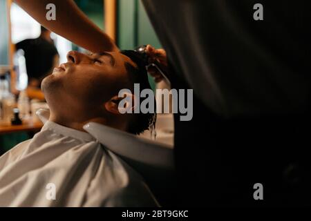 Uomo la cui testa viene lavata nel barbiere. Preparazione dello sposo Foto Stock