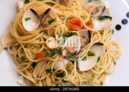 Spaghetti alle vongole, ricetta tradizionale italiana con spaghetti, vongole, pomodori, aglio, peperoncino, prezzemolo e vino bianco Foto Stock