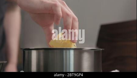 mano dell'uomo mettere la pasta di fettuccine in pentola con acqua bollente Foto Stock