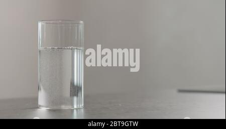 pulire l'acqua fresca nel bicchiere di vetro sul piano di cemento Foto Stock