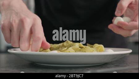 l'uomo ha messo la mozzarella sul pesto fettuccine nel recipiente della pasta piano di appoggio in calcestruzzo Foto Stock