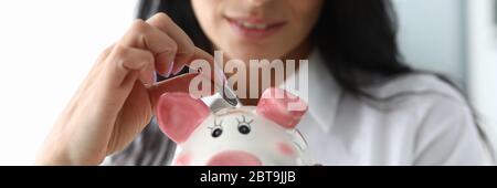 Bella ragazza mette una moneta in ceramica maiale figurina Foto Stock