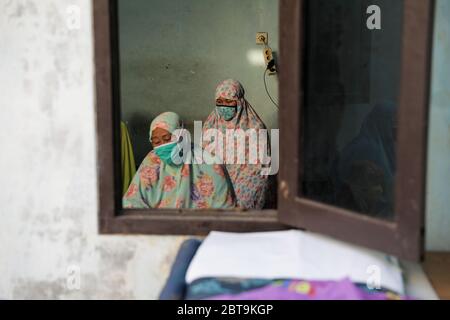 Le donne musulmane indonesiane che indossano maschere sono viste attraverso una finestra che esegue le preghiere di Eid al-Fitr dalla loro casa. Mentre milioni di paesi musulmani accolgono Eid al-Fitr come segno della fine del digiuno del Ramadan nella crescente pandemia di coronavirus, il governo indonesiano ha chiesto ai musulmani di avere le loro preghiere di Eid dalle loro case come precauzione contro la diffusione del Coronavirus. Foto Stock