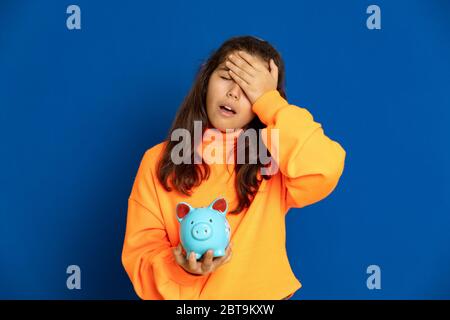 Adorabile ragazza preteen con maglia gialla su sfondo blu Foto Stock