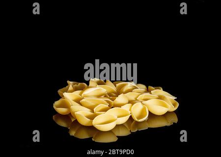 Rigate Conchiglie. Pila di pasta grezza a righe conchiglia isolata su sfondo nero, vista dall'alto. Foto Stock