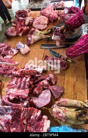 assortimento di carne cruda e coltello sul tavolo di lavoro in legno scuro del macellaio. Vista dall'alto. Foto Stock