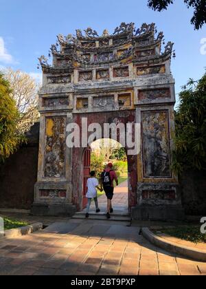 Hue, Vietnam, la città imperiale, i turisti che camminano attraverso un vecchio arco Foto Stock