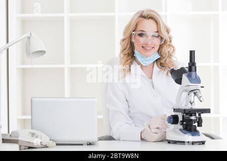 Ritratto di una ricercatrice femminile o di un medico che effettua ricerche utilizzando il microscopio in un laboratorio Foto Stock