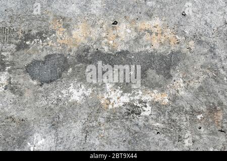 Il vecchio muro di cemento con sfondo grigio, un frammento. Incrinature e macchie. Foto Stock