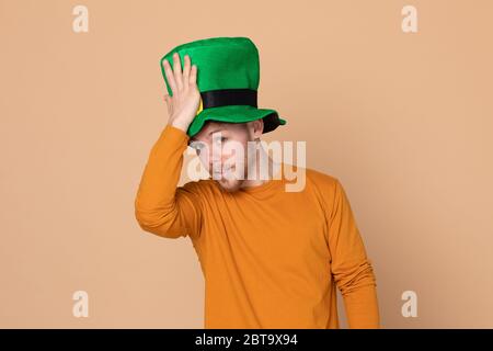 Giovane ragazzo attraente con un cappello verde grande su uno sfondo giallo Foto Stock