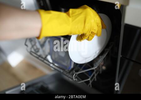 Mani nei guanti mettere la piastra nei piatti in lavastoviglie Foto Stock