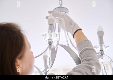 Donna installa le luci a LED nel nuovo lampadario a soffitto Foto Stock