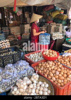 Hue, Vietnam, 20 gennaio 2020 - signora irriconoscibile nel mezzo di assortimento di uova sfuse che vendono dalla fattoria su un mercato, produzione di corto circuito Foto Stock