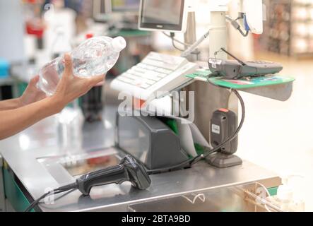 Mano femmina che tiene la bottiglia scannerizzare i prodotti al banco cassa con la macchina di calcolo e scanner nel supermercato. Foto Stock