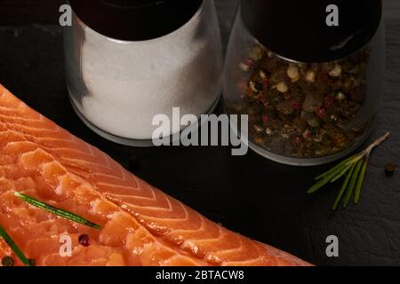 Salmone Pesce cucina Filetto Raw Pepe sale olio di oliva Rosmarino limone Verde Asparagi Tavola di legno Lifestyle concetto sano. Foto Stock