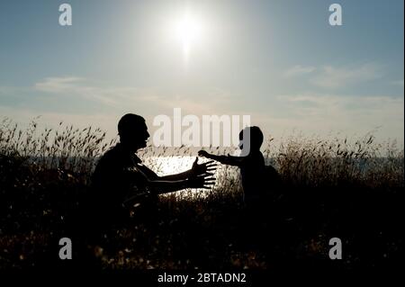 amore abbraccio concetto di bambino giovane famiglia che corre al suo padre a braccia aperte mare tramonto all'aperto Foto Stock