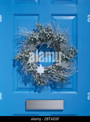 Corona di Natale in argento sulla porta blu. Foto Stock