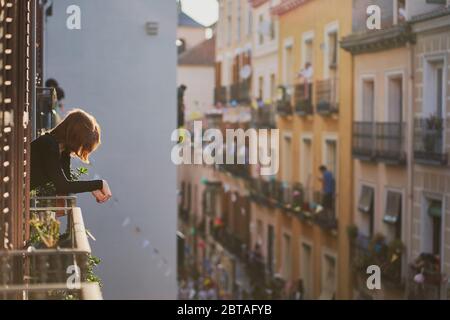 Una donna guarda fuori dalla sua finestra balcone alle 20:00 applausi / festa per i lavoratori di emergenza in Spagna. Durante il periodo di blocco Covid-19 a Madrid, maggio 2020 Foto Stock