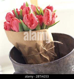 Bouquet di tulipani rosa avvolti in carta marrone Foto Stock