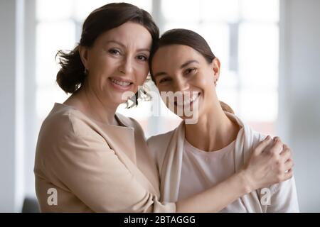 Ritratto di mamma matura sorridente e figlia adulta abbracciare Foto Stock