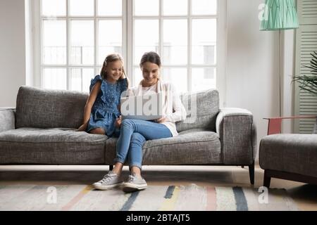 Felice mamma e bambina che usano il computer portatile a casa Foto Stock