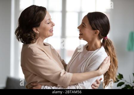 Mamma sorridente di mezza età e figlia di ringhiante abbracciano a casa Foto Stock