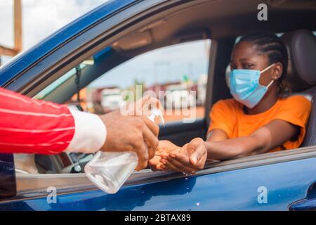 Donna in auto che riceve gel di alcol o gel igienizzante per lavare le mani, virus corona o protezione Covid-19. Foto Stock