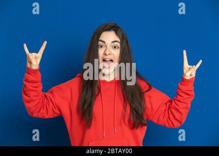 Giovane ragazza brunetta con una maglia rossa su sfondo blu Foto Stock