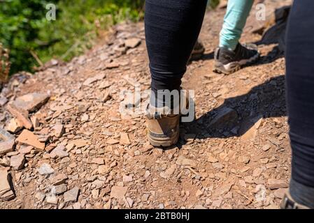 Una donna in piedi in pelle specializzata, scarpe da montagna su una superficie di pietra, ardesia. Foto Stock