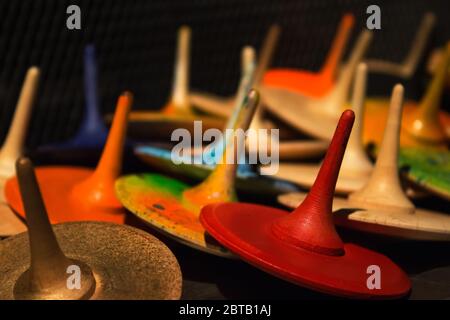 Vista in primo piano dei colorati giocattoli in legno dipinti a mano - top con spina o whirliggs come sfondo creativo con bokeh dorato chiaro sfocato Foto Stock