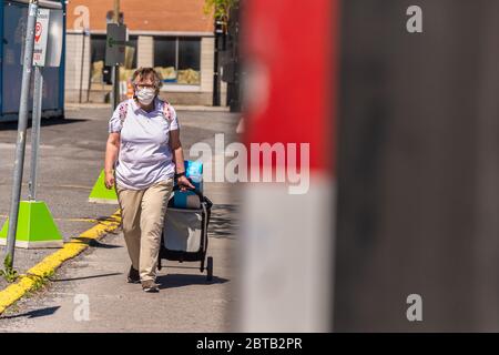 Montreal, CA - 23 Maggio 2020: Donna con maschera facciale per la protezione dal COVID-19 sulla via Maisonneuve Foto Stock