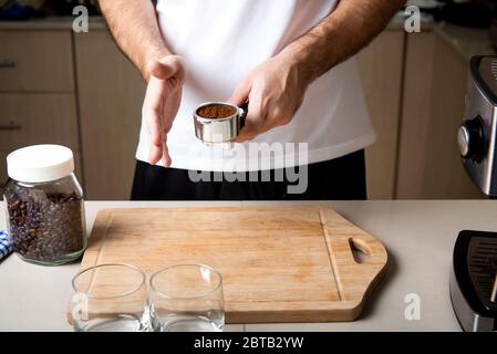 Uomo che dispone la polvere macinata di caffè nel cestino portafiltro. Home barista concetto di stile di vita indoor Foto Stock