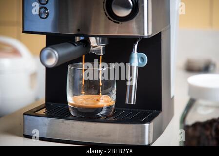 Espresso da una macchina per il caffè in un'altra closeup di vetro Foto Stock