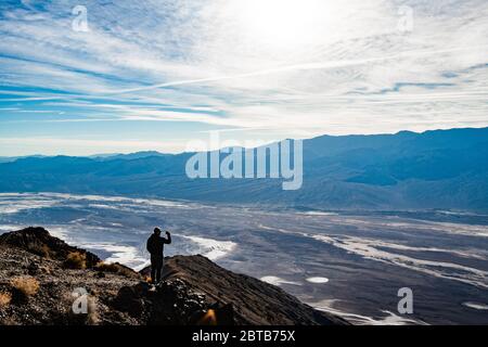 Uomo che fa una foto sul telefono cellulare al punto panoramico di Dante's View sul lato nord del coffin Peak, lungo la cresta delle Black Mountains, Death Valley Foto Stock