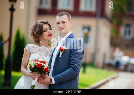 Elegante sposa e lo sposo che pongono insieme all'aperto su un giorno di nozze Foto Stock