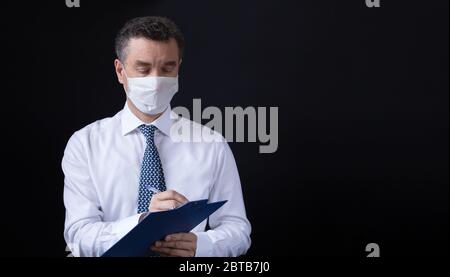 Un uomo che indossa la maschera medica e lavora da casa Foto Stock