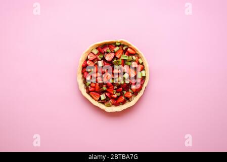 Fragole e rabarbaro affettato in una crosta di torta pronta per la cottura. Preparazione di una torta di rabarbaro-fragole, vista dall'alto. Foto Stock