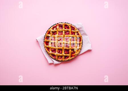 Rabarbaro fatto in casa e torta di fragole su sfondo rosa, sopra la vista. Flatlay con torta di crosta di gres appena sfornata Foto Stock