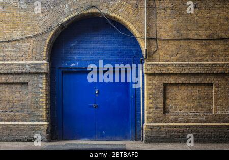 Porta blu in un muro di mattoni. Foto Stock