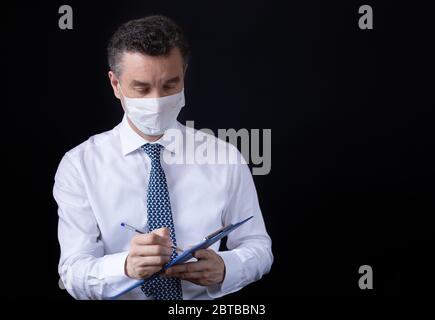 Un uomo che indossa la maschera medica e lavora da casa Foto Stock