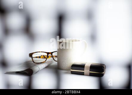 Tazza di caffè del mattino, occhiali, confezione regalo confezionata, giornale con crossword su sfondo chiaro, messa a fuoco morbida. Concetto di Giornata dei Padri felici Foto Stock