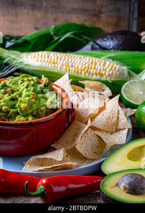 Salsa di guacamole con mais arrosto e ingredienti crudi Foto Stock