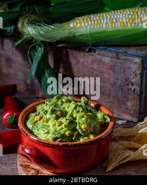 Salsa di guacamole con mais arrosto e ingredienti crudi Foto Stock