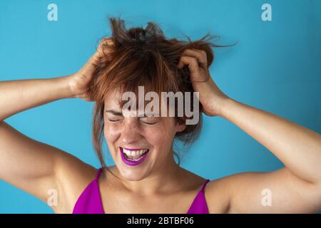 Stressata giovane donna che tira i capelli mentre urla Foto Stock