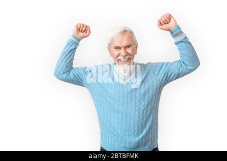Stile libero. Uomo anziano bearded in maglione in piedi isolato su mani bianche su sorridente riuscito Foto Stock