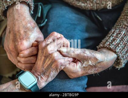 Aggrappando le loro vecchie mani insieme, ancora innamorate nei loro anni '90, insieme, sia vivendo che dormendo nel soggiorno al piano inferiore a causa della loro salute malata Foto Stock