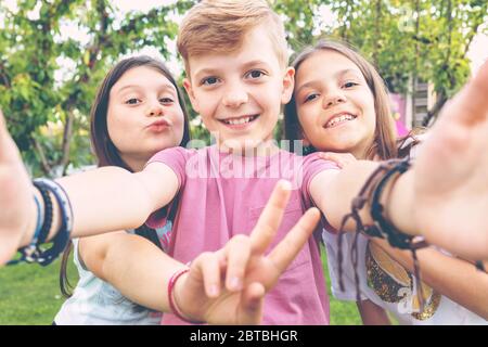 Felici i migliori amici bambini che prendono selfie all'aperto in festa in giardino Foto Stock