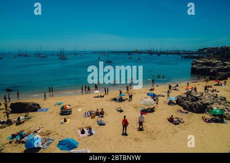 Cascais, Portogallo - 24 maggio 2020: Spiaggia di sabbia a Cascais vicino durante l'estate. Questa spiaggia è conosciuta come Praia da Conceicao. Beachgoears che pratica soc Foto Stock