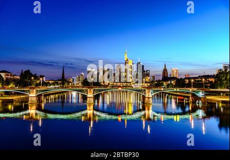 Splendida vista sullo skyline cittadino del centro di Francoforte sul meno, ponte con luci durante il tramonto all'ora blu, sera e notte. Finanza europea Foto Stock